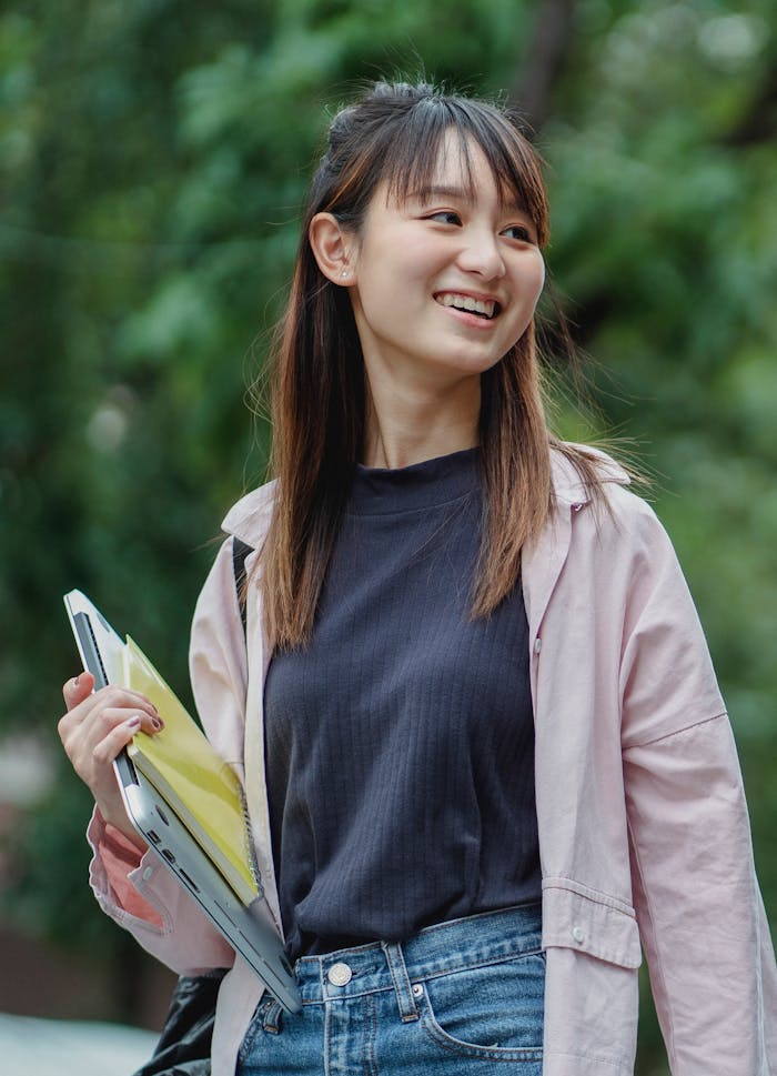 Happy Asian female student waling in park